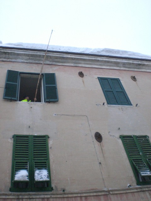 Uno dei militi alle prese con il pericolo caduta neve e ghiaccioli dai tetti